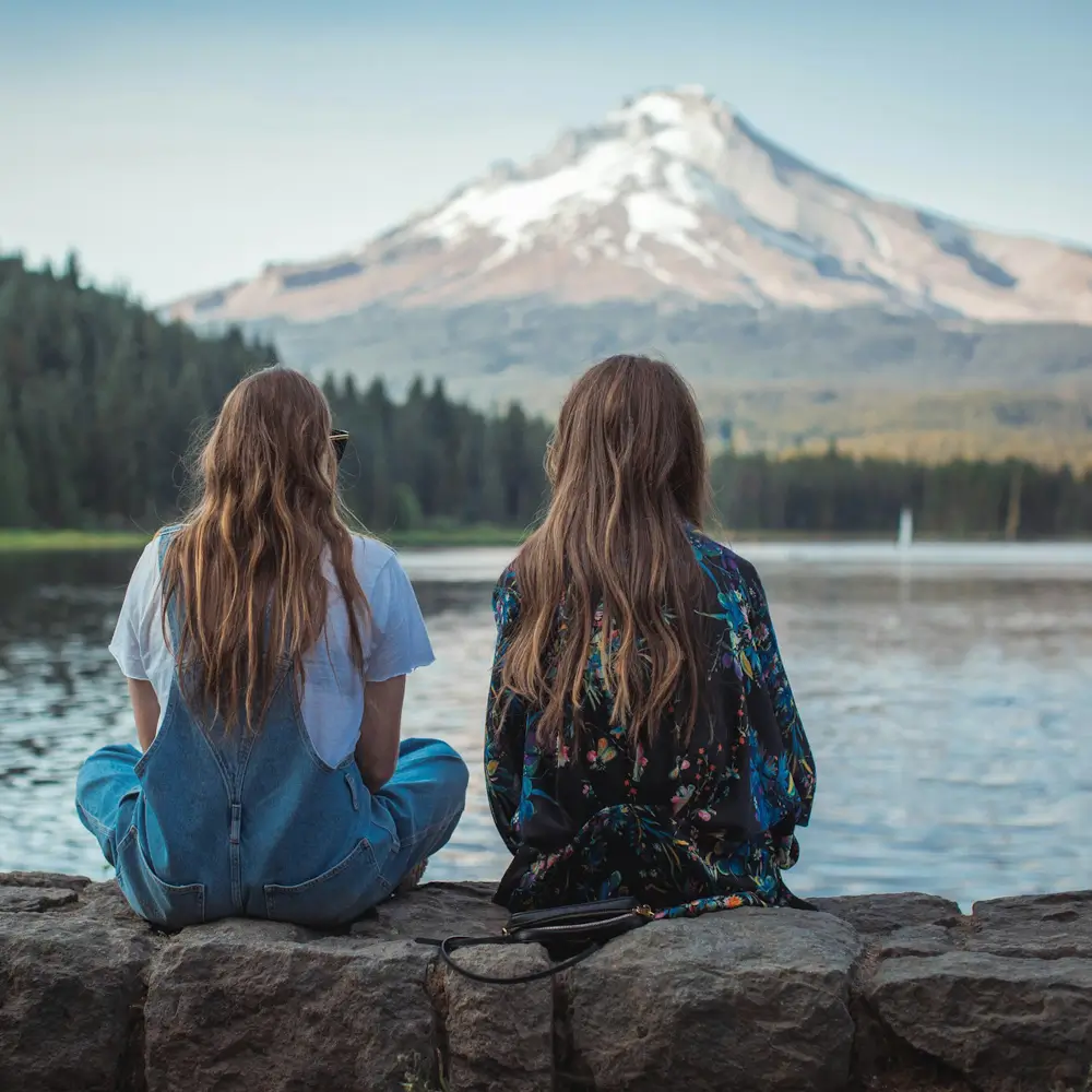 Two girls looking across water to a mountaintop